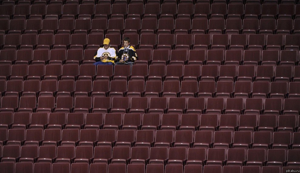 Пара фанатов Бостонского Бруинс сидит на пустой трибуне после поражения их команды в плэйоффе, Ванкувер, Колумбия.